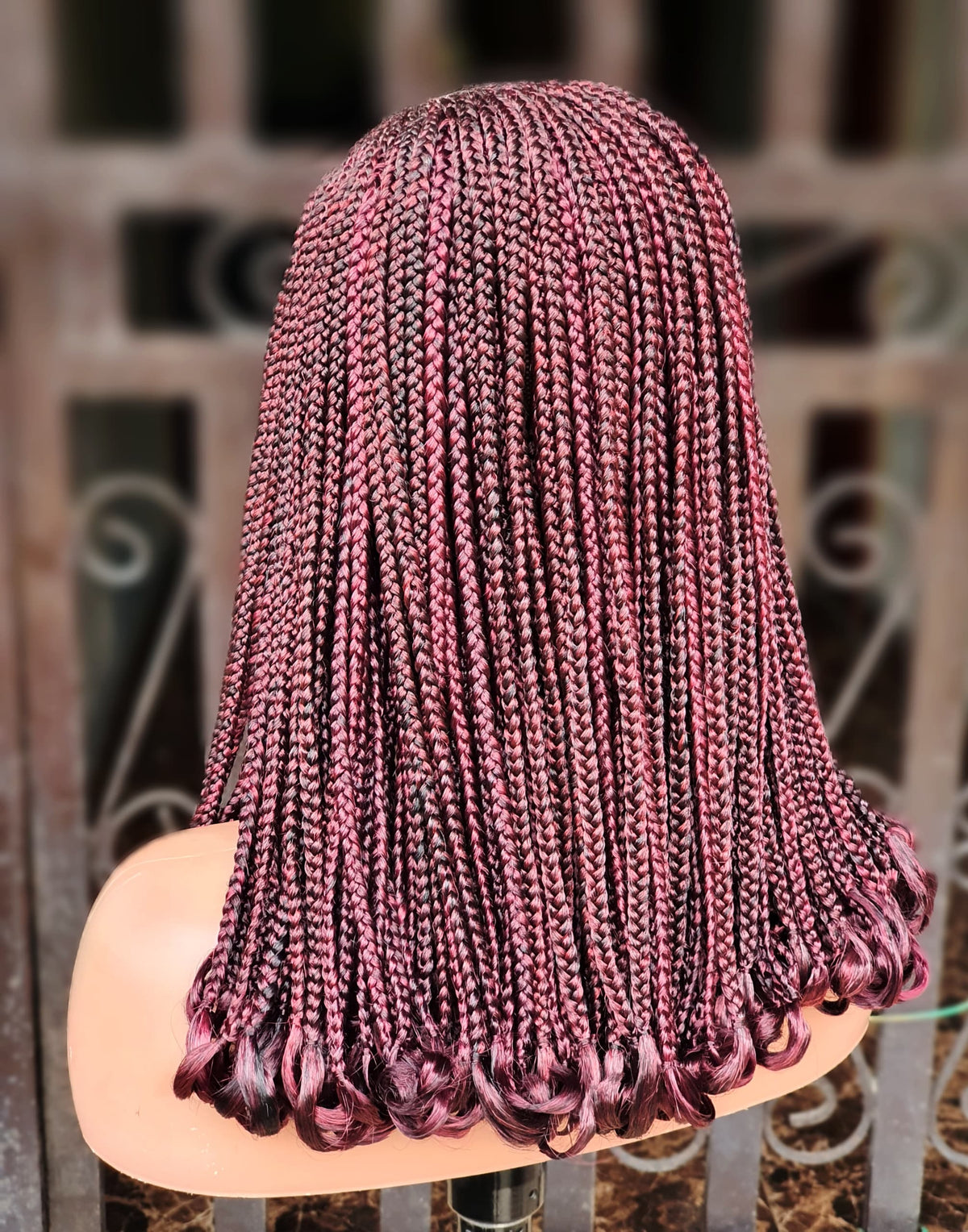 Back view of burgundy C-cut cornrow wig and curled braid ends